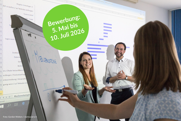 Zusehen sind zwei Frauen und ein mann, die vor einer Präsentation und schreibbereit an einer Plipchart stehen und gutgelaunt miteinander sprechen.