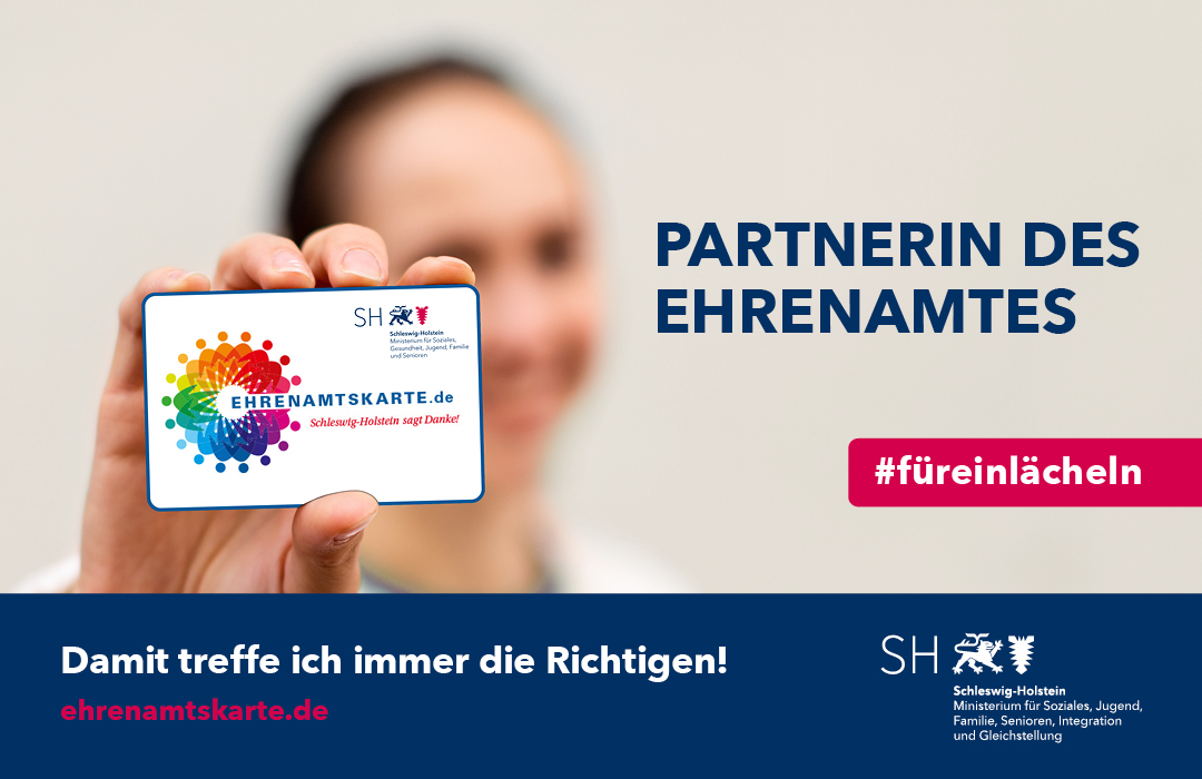 Eine Frau halt eine Ehrenamtskarte in die Kamera.