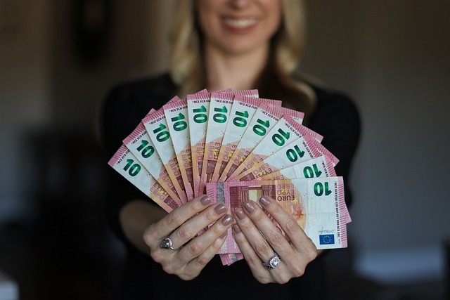 Eine Frau hält mehere 10€ Scheine wie einen Fächer vor sich.