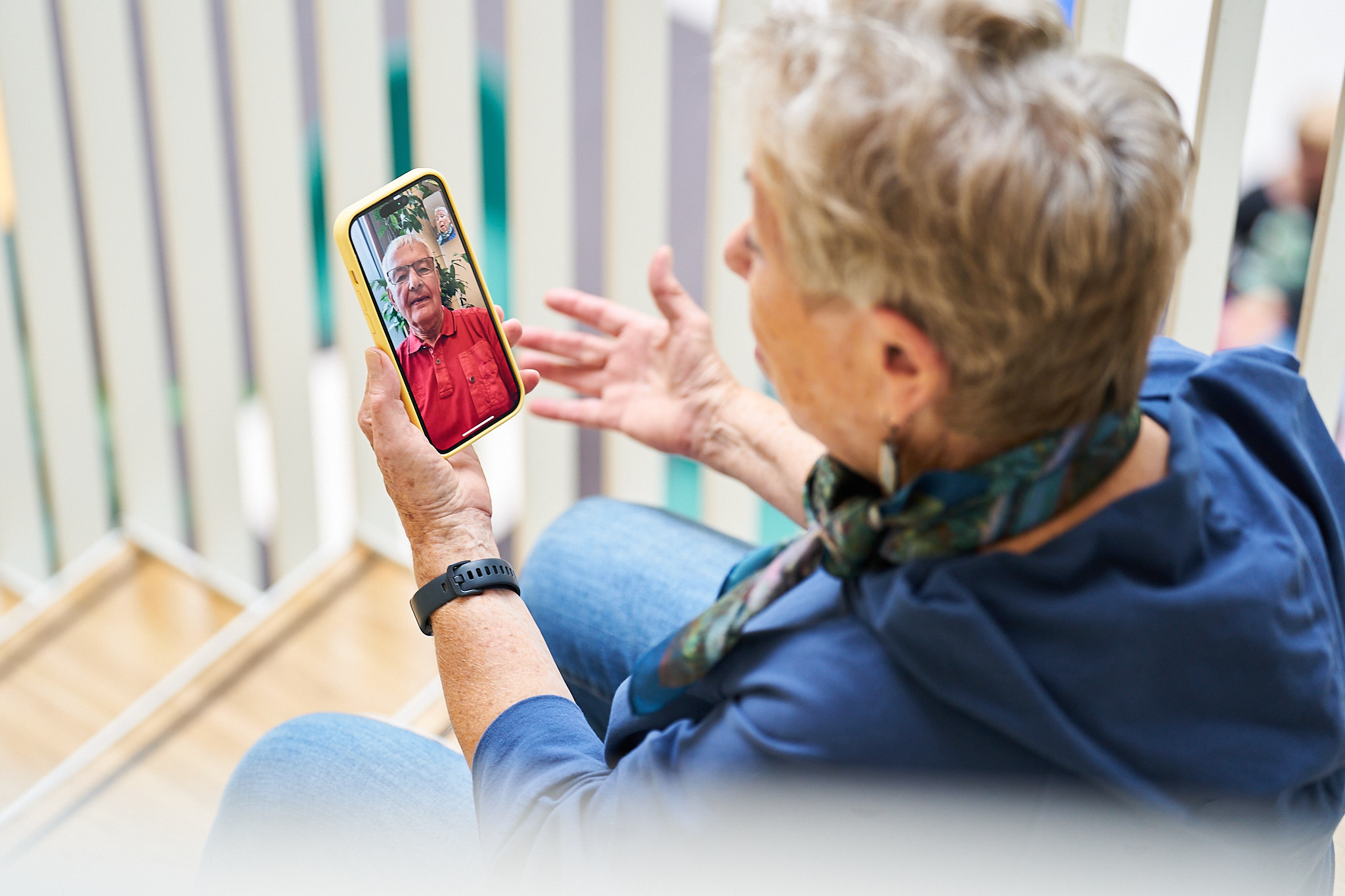 Eine Frau sitzt auf einer Treppe und kommuniziert per Video mit einem Handy mit einem Mann